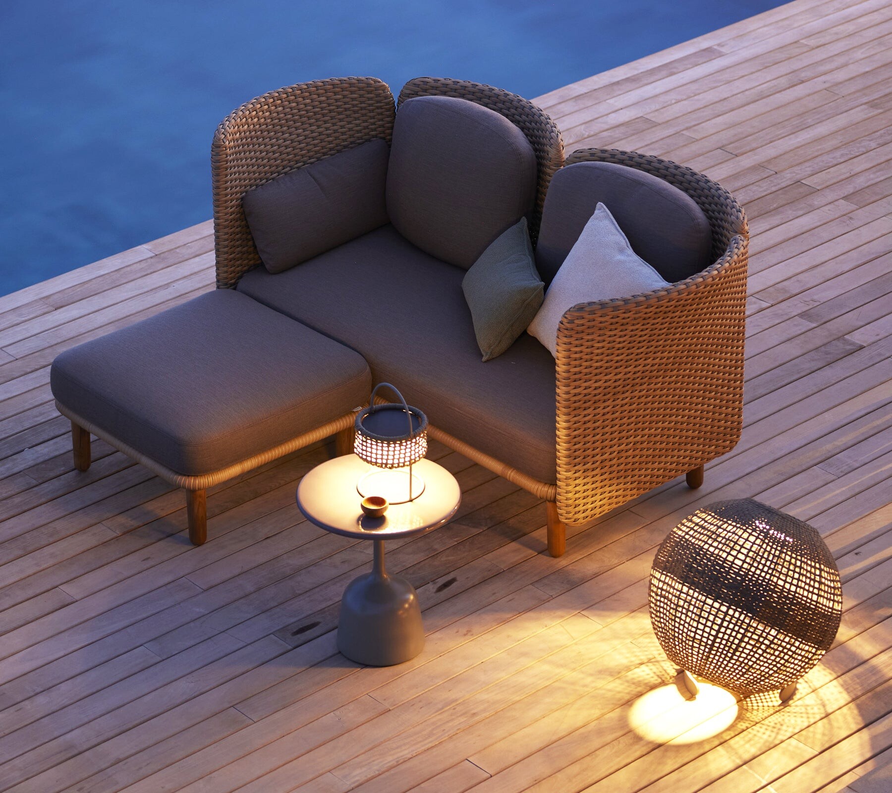 Cane-line Arch lounge set with lanterns on a wood deck at dusk