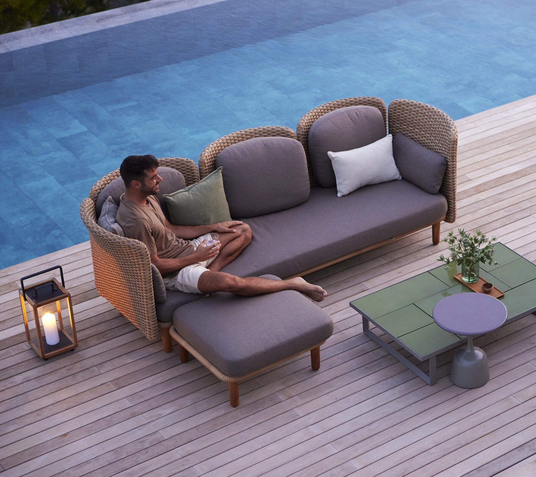 Cane-line Arch outdoor sofa by a pool in the evening