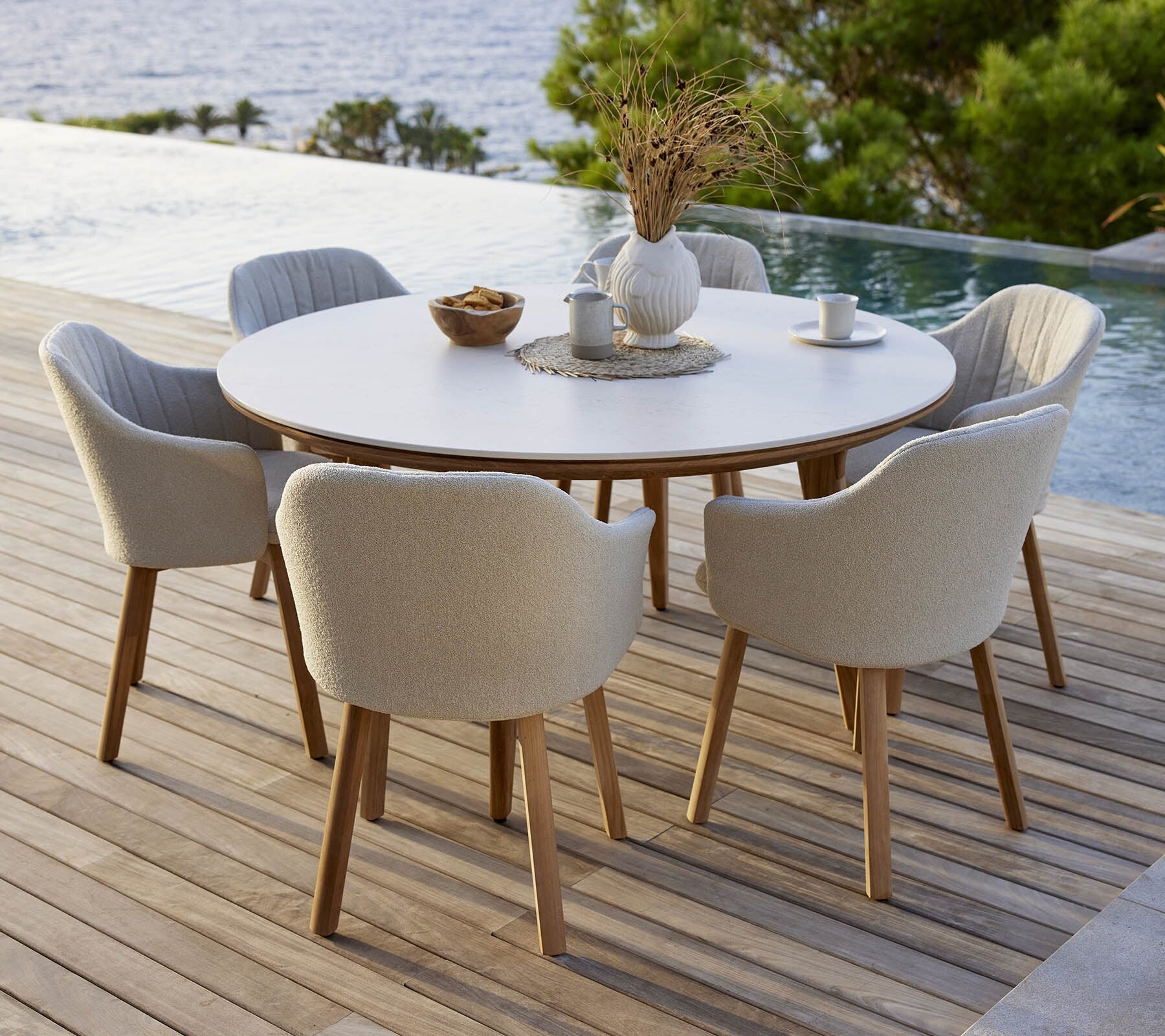 Cane-line Aspect round dining table with grey chairs on a pool deck