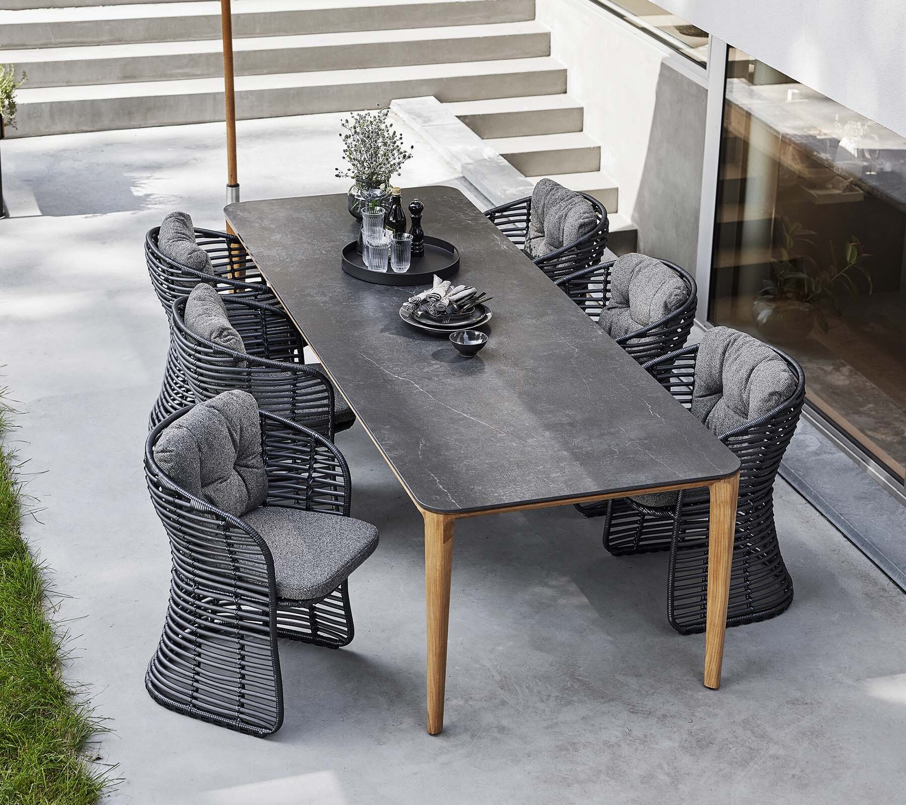 Cane-line Aspect rectangular dining table with dark rope chairs on a terrace