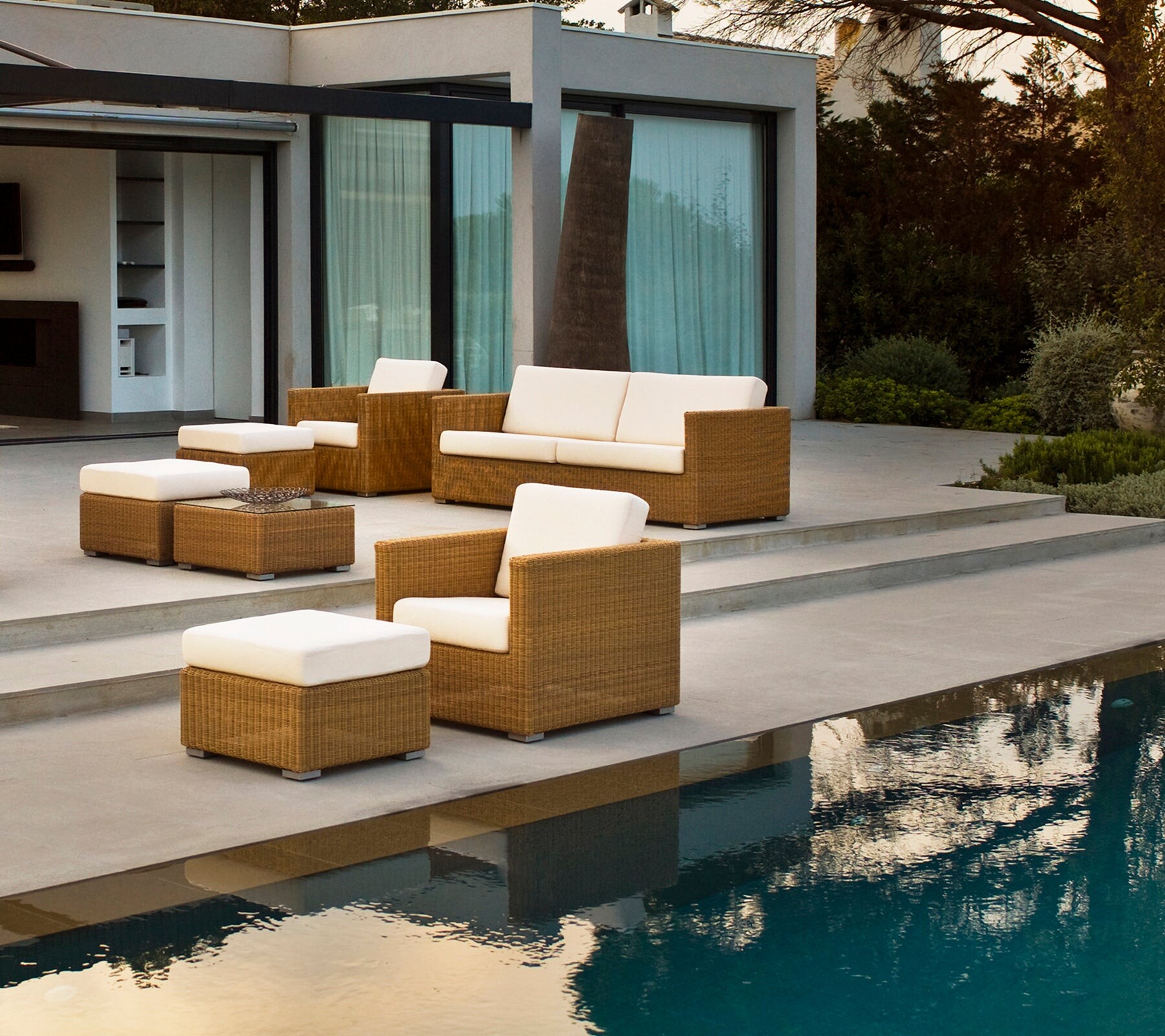 Cane-line Chester footstools beside a pool