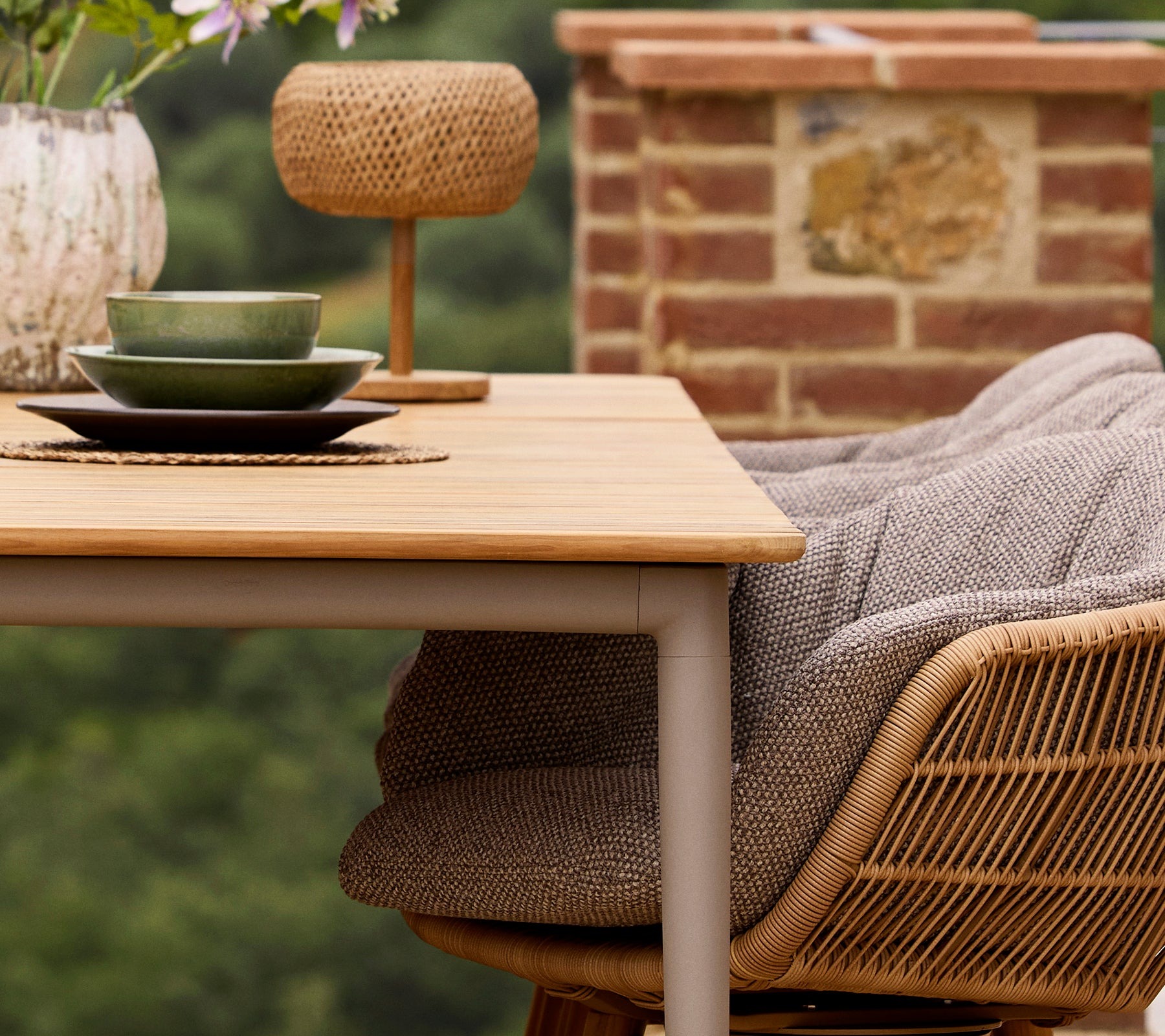 Cane-line Core teak dining table set with chairs on a terrace overlooking olive groves