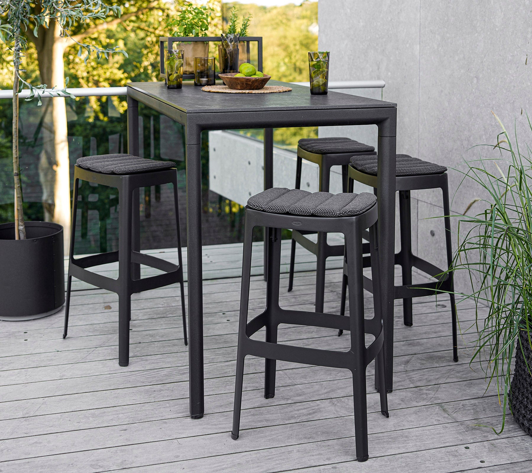 Cane-line Cut outdoor bar table and stools in lava grey on a terrace