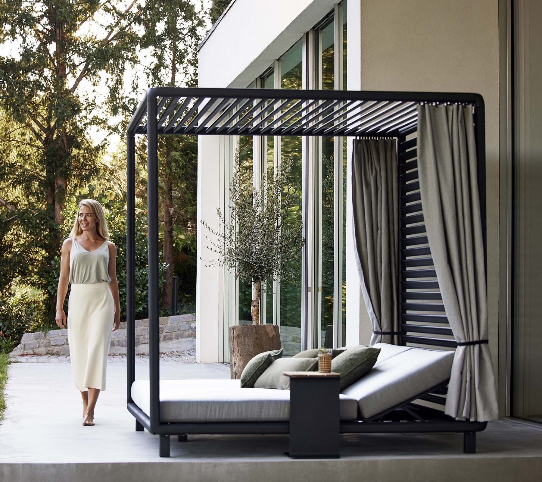Cane-line Laze outdoor cabana daybed with curtains on a terrace at dusk