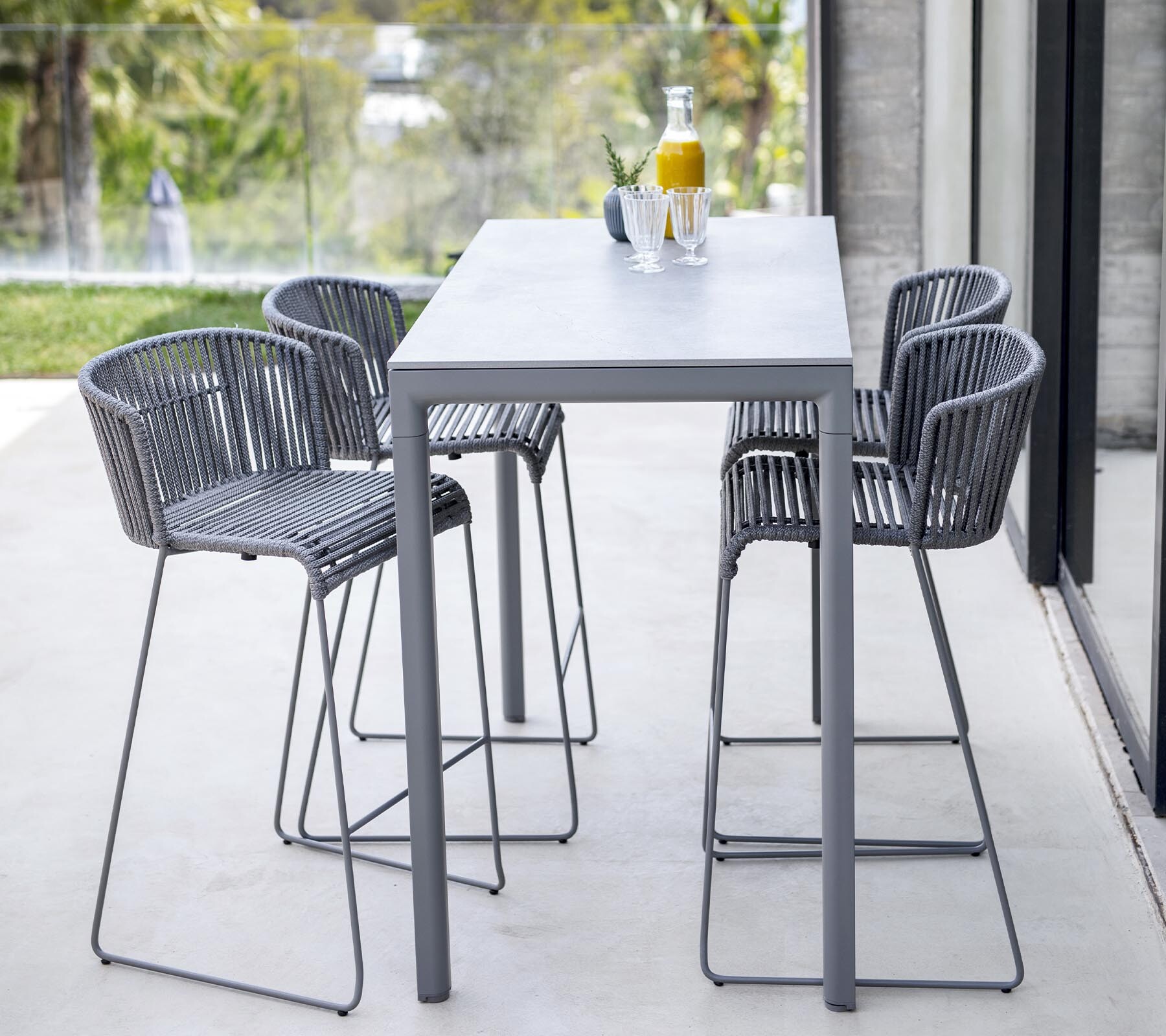 Cane-line Moments bar table and bar chairs in a garden