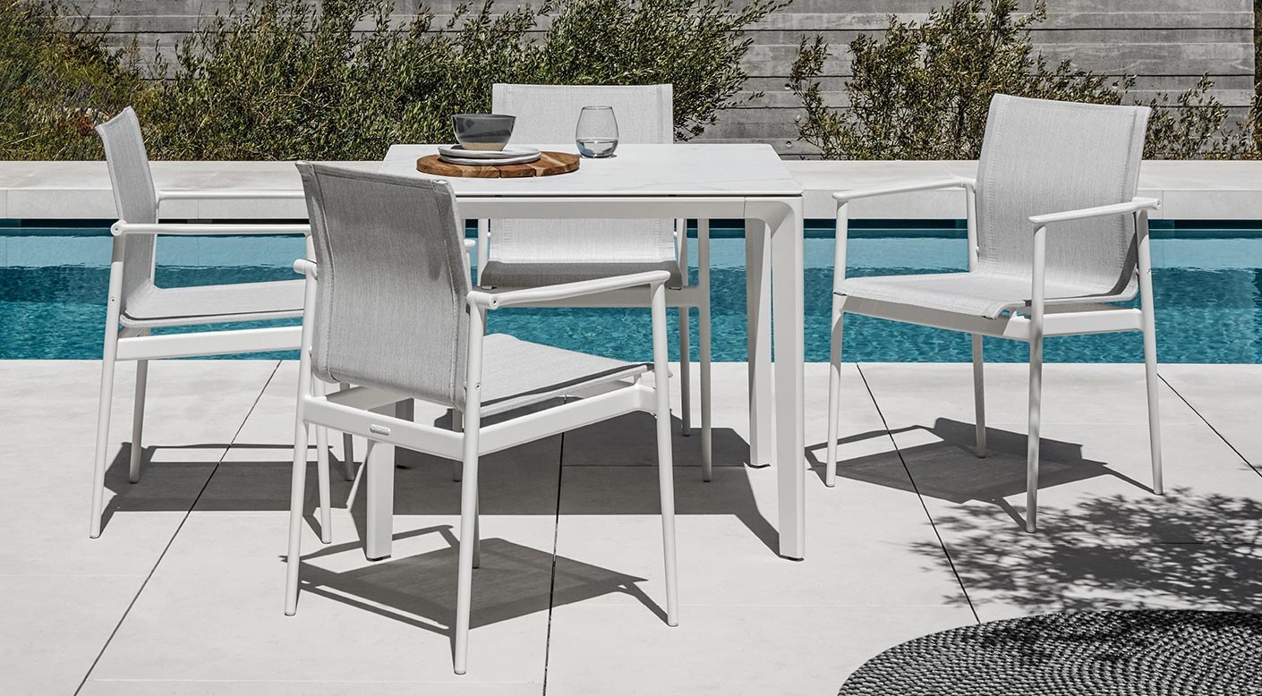 180 dining collection by Henrik Pedersen for Gloster, with white aluminum frames and sling seats by a pool